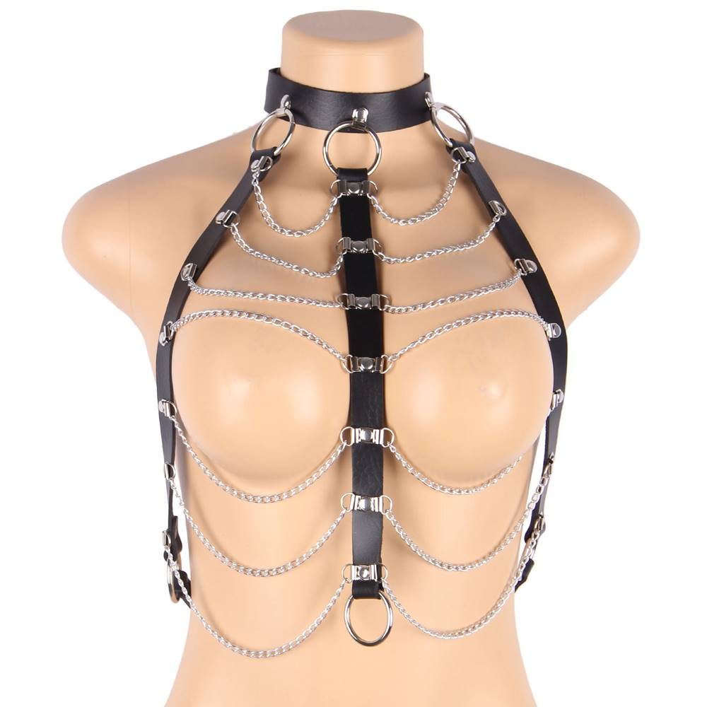 Black leather harness bra with multiple silver chains and O-ring details styled over black lingerie